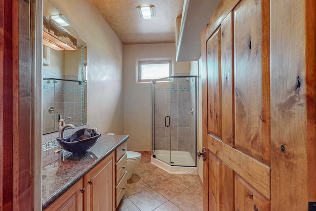 bathroom featuring toilet, vanity, tile patterned floors, and a shower with door