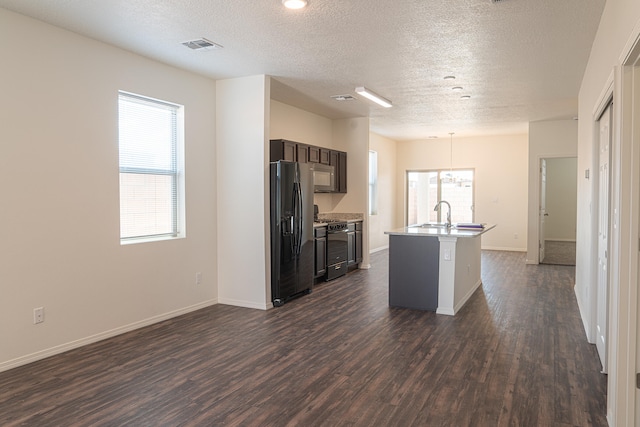 kitchen with a kitchen island with sink, dark wood-type flooring, black appliances, and a textured ceiling