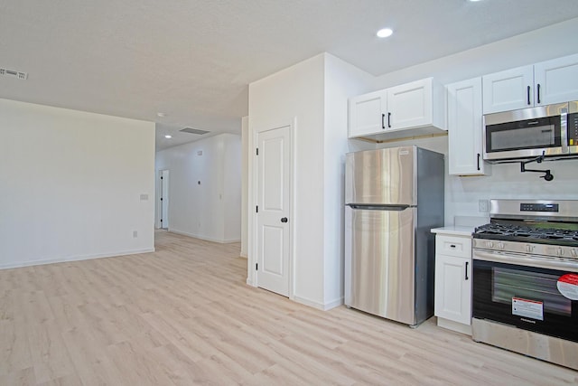 kitchen featuring appliances with stainless steel finishes, white cabinets, and light hardwood / wood-style floors