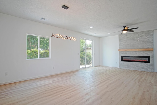 unfurnished living room featuring light hardwood / wood-style flooring, a fireplace, and a textured ceiling