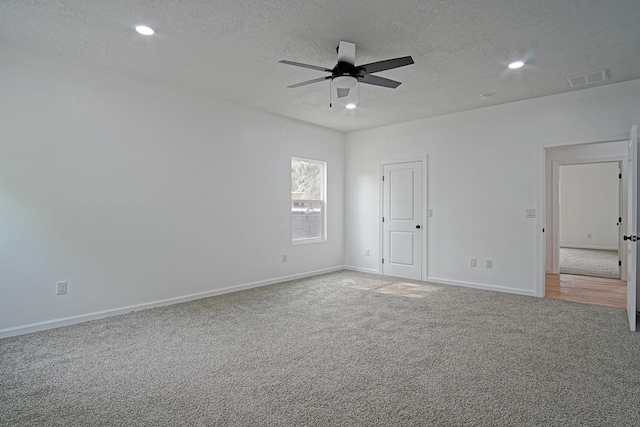 carpeted spare room featuring ceiling fan and a textured ceiling