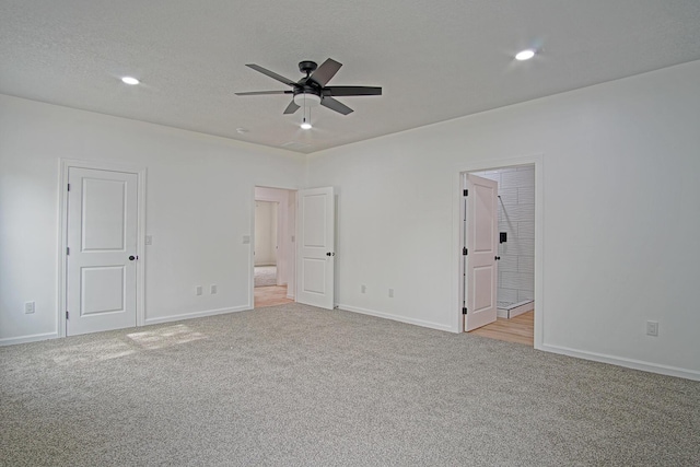 unfurnished bedroom with light carpet, ensuite bath, a textured ceiling, and ceiling fan