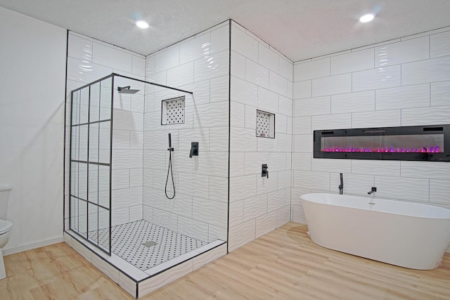 bathroom with toilet, plus walk in shower, hardwood / wood-style floors, and tile walls