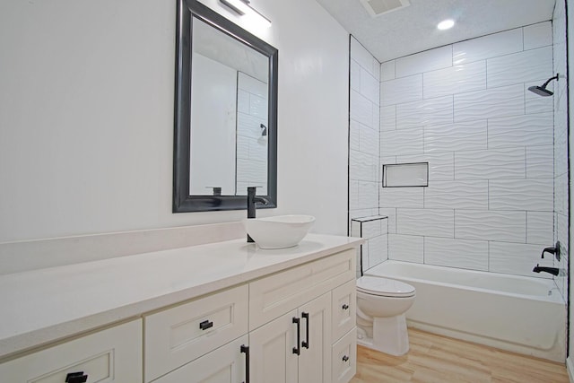 full bathroom featuring vanity, wood-type flooring, toilet, and tiled shower / bath