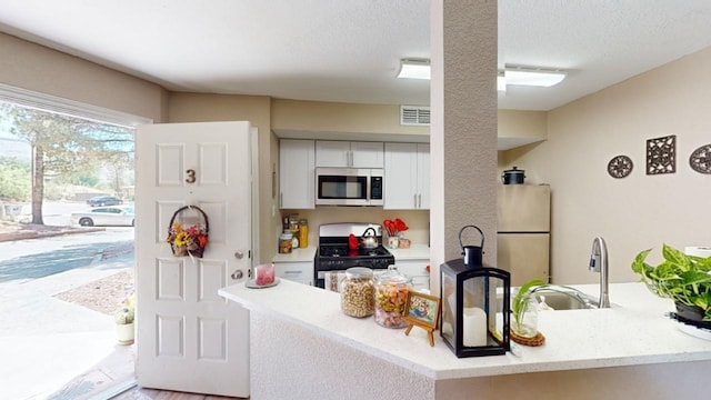 kitchen with black range with gas cooktop, a textured ceiling, sink, white cabinetry, and fridge