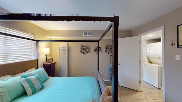 bedroom featuring ensuite bathroom, light hardwood / wood-style floors, and stacked washing maching and dryer