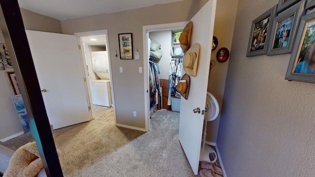 hall with light carpet and stacked washing maching and dryer