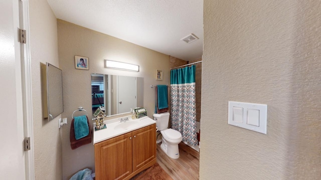 bathroom featuring walk in shower, vanity, a textured ceiling, wood-type flooring, and toilet