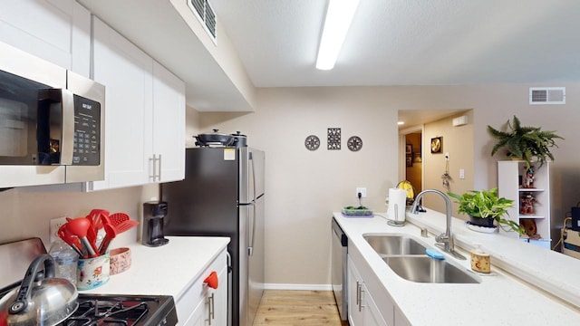 kitchen featuring light stone countertops, stainless steel appliances, sink, light hardwood / wood-style flooring, and white cabinetry