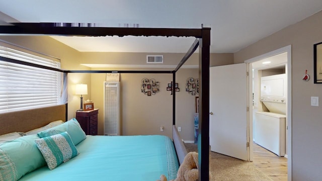 bedroom with stacked washing maching and dryer and light hardwood / wood-style floors