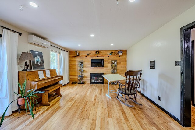 dining room featuring light hardwood / wood-style floors, a wall mounted AC, and wooden walls