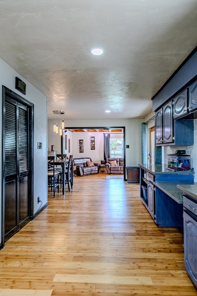 kitchen with blue cabinets, light hardwood / wood-style flooring, and pendant lighting