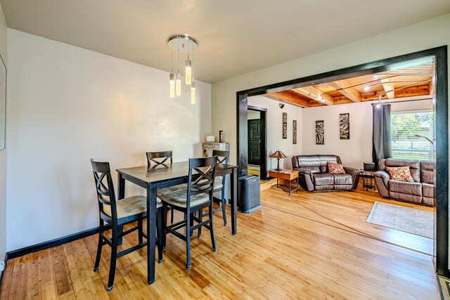 dining space featuring beamed ceiling and light wood-type flooring