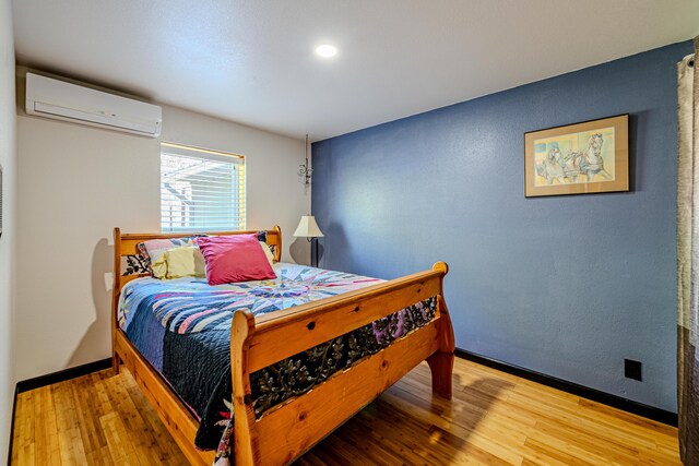 bedroom with a wall unit AC and wood-type flooring