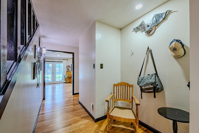 corridor with light hardwood / wood-style floors and french doors