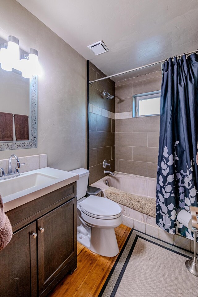 full bathroom with shower / tub combo, vanity, toilet, and hardwood / wood-style floors