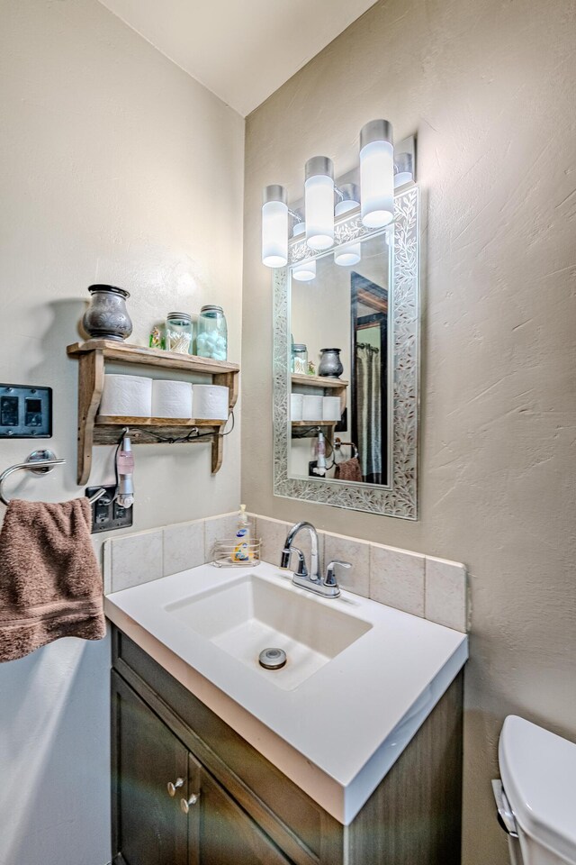 bathroom featuring vanity, toilet, and tasteful backsplash