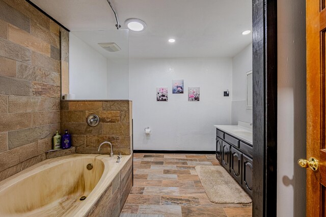 bathroom with a relaxing tiled bath, vanity, and tile floors