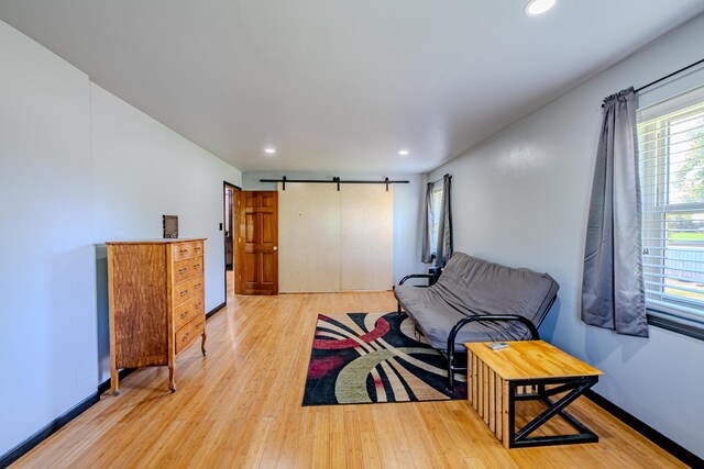 living room with a barn door and hardwood / wood-style flooring