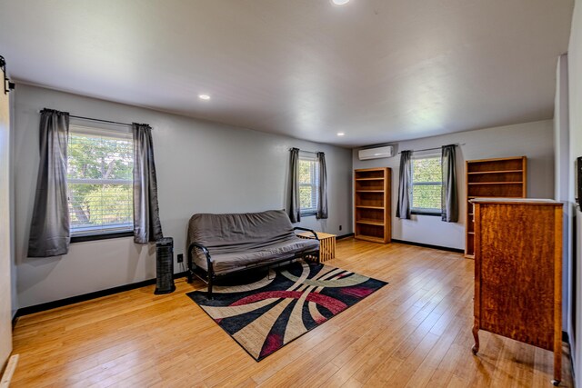 living room featuring light wood-type flooring and a wall mounted air conditioner