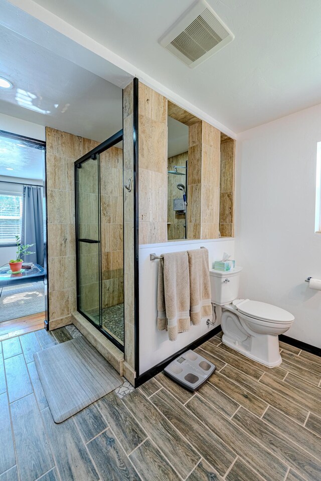 bathroom featuring a shower with shower door and toilet