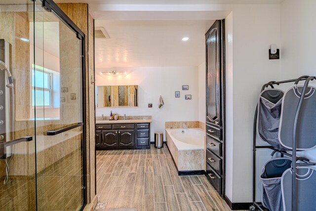 bathroom featuring hardwood / wood-style floors, vanity, and plus walk in shower