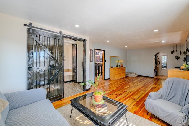 living room with a barn door and wood-type flooring