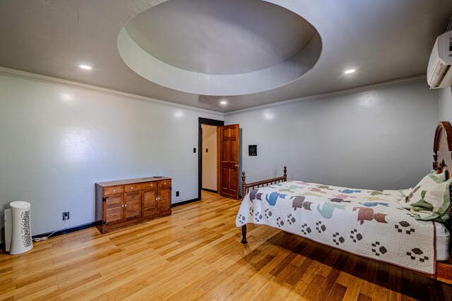 bedroom with a tray ceiling, light wood-type flooring, and a wall mounted air conditioner