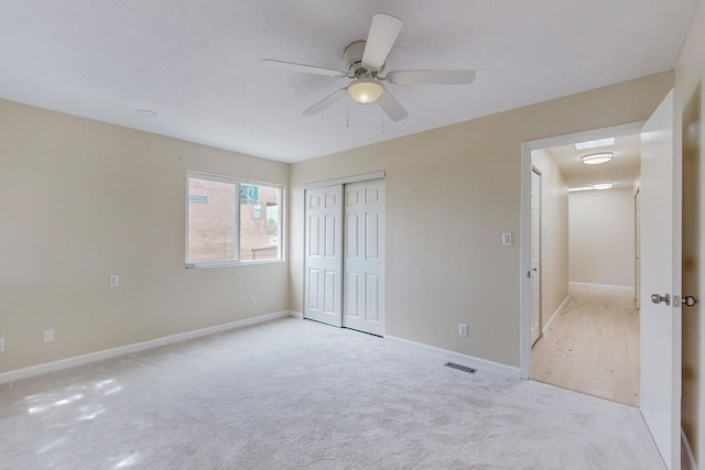 unfurnished bedroom with ceiling fan, light colored carpet, and a closet