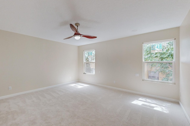 carpeted spare room featuring ceiling fan and a healthy amount of sunlight