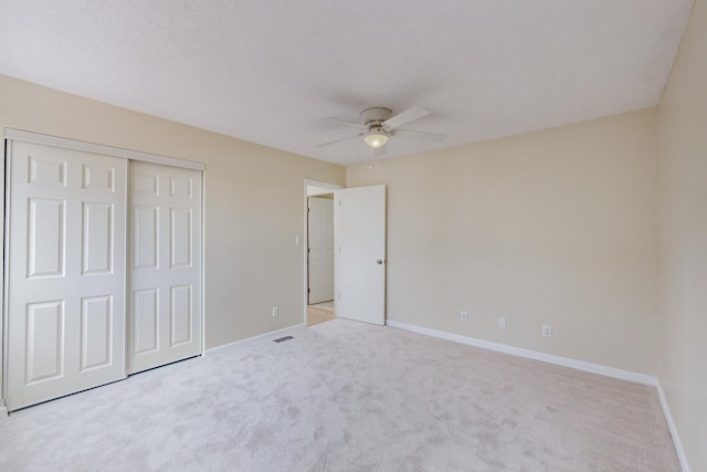 unfurnished bedroom featuring light carpet, a closet, and ceiling fan