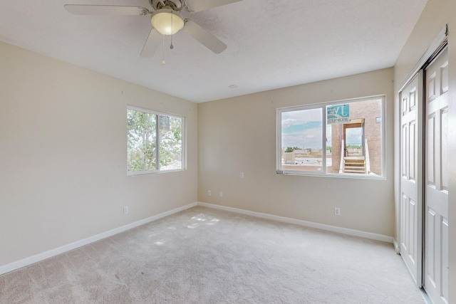 unfurnished bedroom featuring light carpet, a closet, and ceiling fan