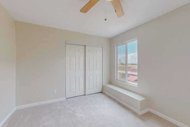 unfurnished bedroom featuring ceiling fan, a closet, and light colored carpet