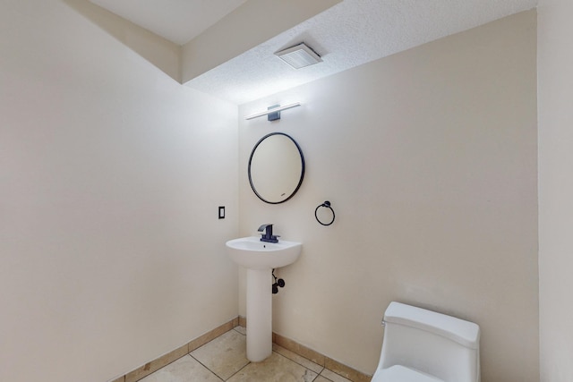 bathroom with tile patterned floors, a textured ceiling, and toilet