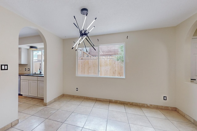 unfurnished dining area featuring light tile patterned floors, a notable chandelier, and sink