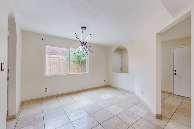 unfurnished dining area with light tile patterned floors, a chandelier, and a textured ceiling