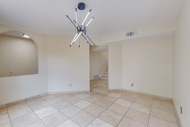 spare room with a chandelier and light tile patterned floors