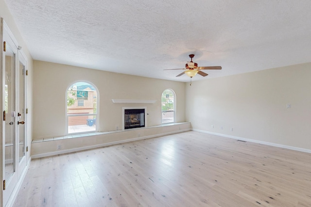 unfurnished living room featuring a textured ceiling, light hardwood / wood-style flooring, and ceiling fan