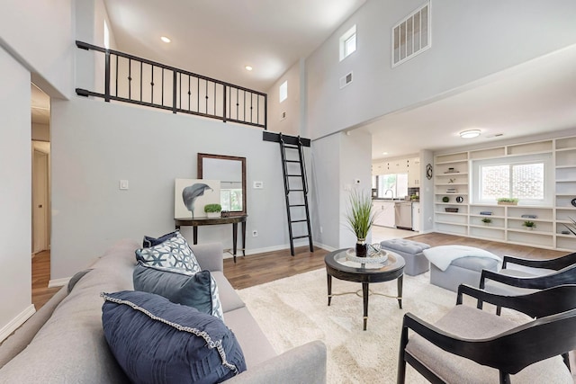 living room featuring a high ceiling, sink, and hardwood / wood-style flooring