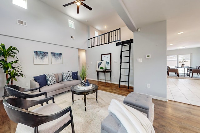 living room with a high ceiling, ceiling fan, hardwood / wood-style flooring, and a barn door