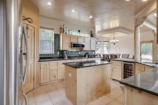 kitchen featuring stainless steel appliances, wine cooler, a wealth of natural light, and a center island