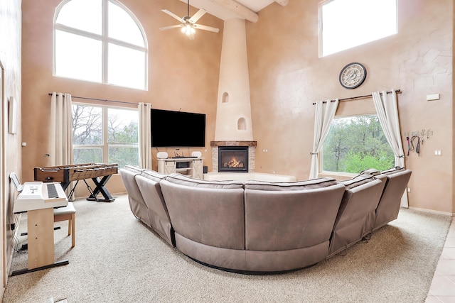 carpeted living room with a high ceiling, beam ceiling, a large fireplace, and plenty of natural light