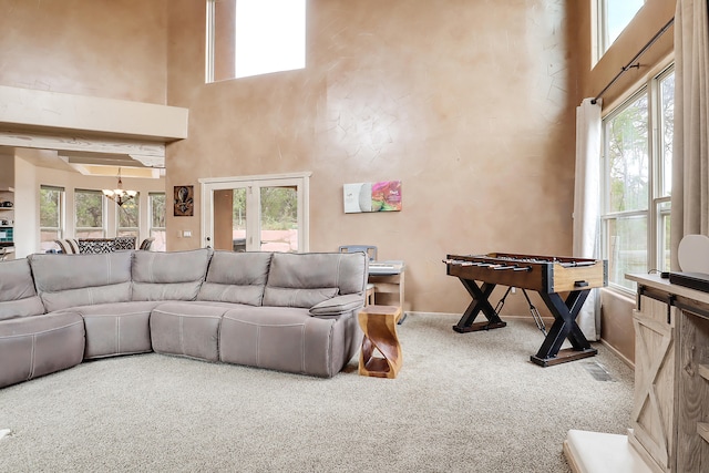 living room featuring a healthy amount of sunlight, a high ceiling, carpet, and a chandelier