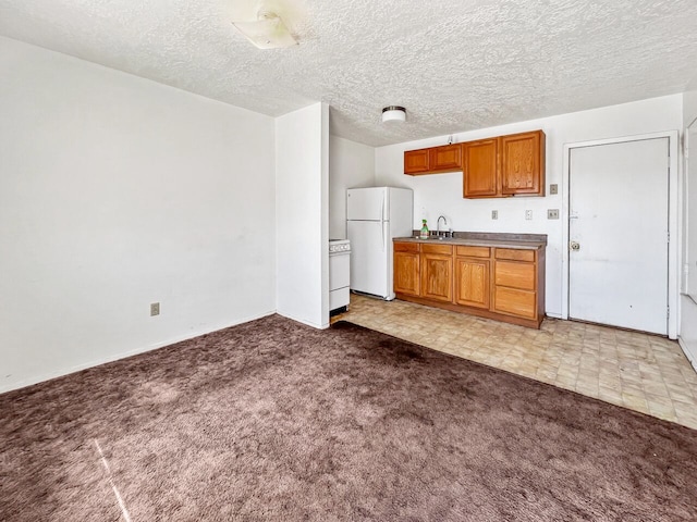 kitchen featuring light colored carpet, sink, white appliances, and a textured ceiling