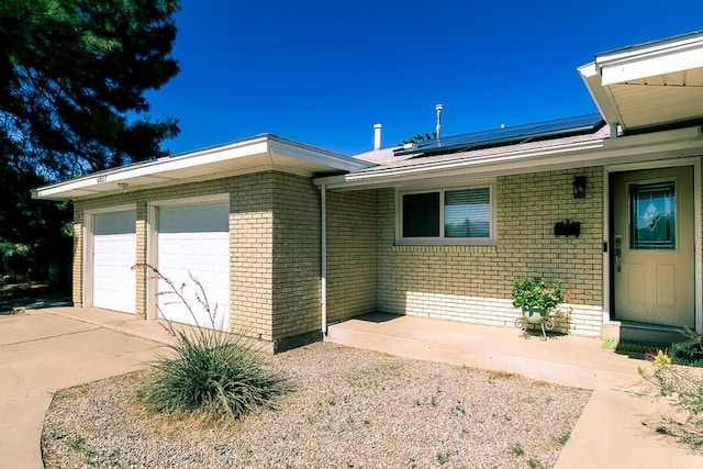 view of exterior entry featuring a garage and solar panels