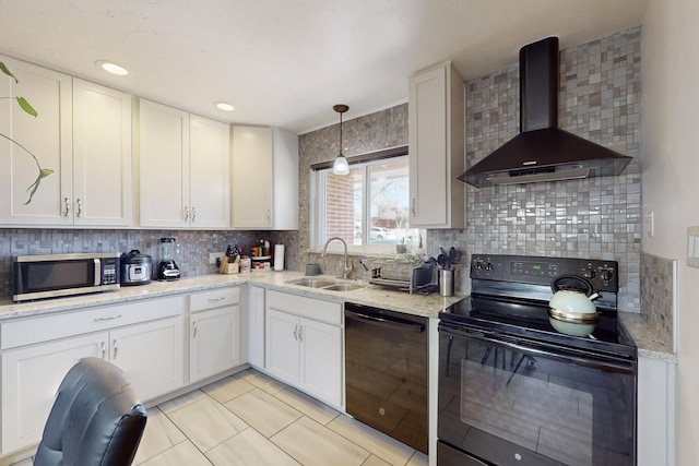 kitchen with wall chimney exhaust hood, pendant lighting, black appliances, white cabinets, and sink