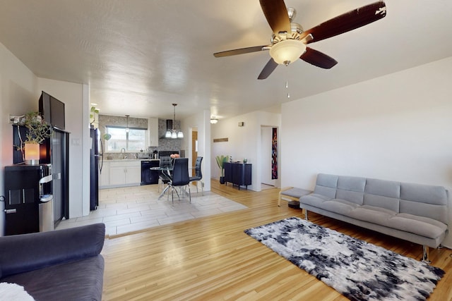 living room featuring ceiling fan, light wood-type flooring, and sink