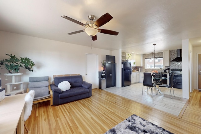 living room with ceiling fan with notable chandelier, sink, and light hardwood / wood-style flooring