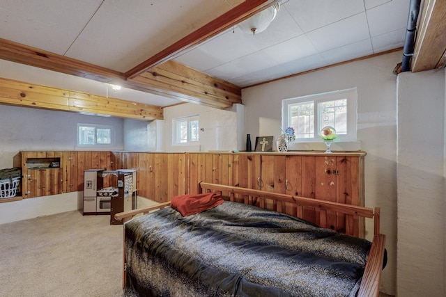 carpeted bedroom featuring ornamental molding, wood walls, and beamed ceiling