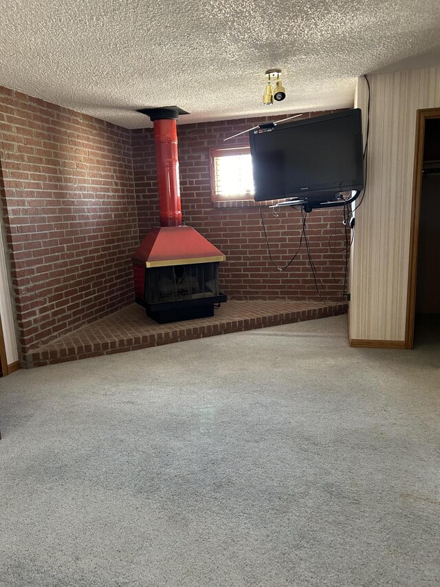 unfurnished living room with carpet, a wood stove, and brick wall